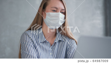 Young Caucasian doctor woman working from home online using laptop, consulting people on quarantine wearing face mask. Young Caucasian doctor woman working from home online using laptop, consulting people on quarantine wearing face mask. 64987009