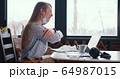 Side view young healthy happy woman making video call on laptop to chat with friends from home with face mask on neck. 64987015