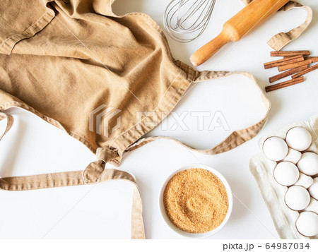 Ocher apron and various baking ingredients and kitchen utensils  64987034