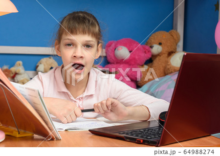 Girl yawns from boring distance learning 64988274
