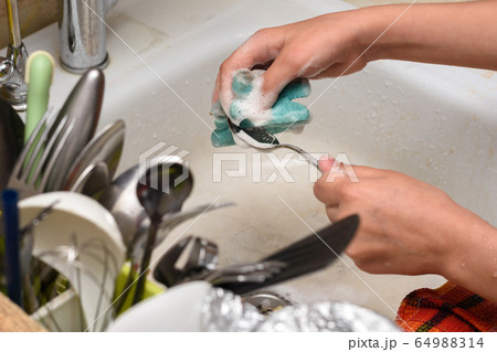 Hands wash the dishes in the old sink, in the 64988314