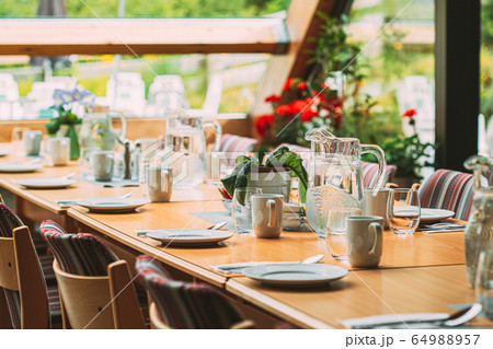 Cozy Interior Of Summer Cafe. Jug Of Water On Table And Cutlery Laid Out 64988957