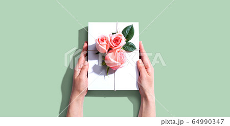 Female hands holding a gift box with pink roses 64990347