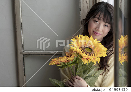 ひまわりを持つ女性 64993439