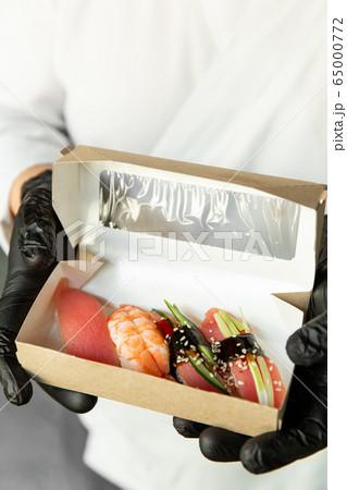 Beautiful sushi in craft packaging for delivery in the hands of a chef. Food delivery. Food at home. Delivery concept. Beautiful sushi in craft packaging for delivery in the hands of a chef. Food delivery. Food at home. Delivery concept. 65000772