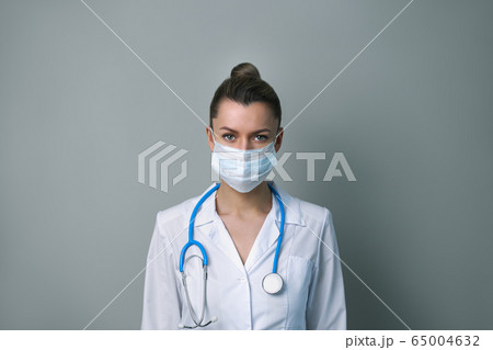 A female doctor in a white robe and mask with a stethoscope. 65004632