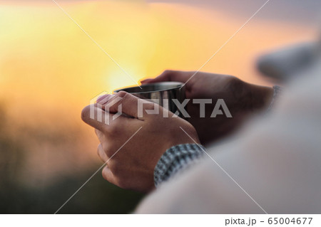 A couple in love, a man and a woman are holding metal hiking circles against the background of the sunset. A cozy evening. 65004677