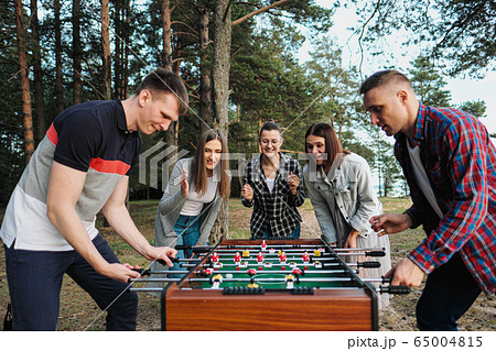 Friends play table football or kicker outdoors. Players and fans rejoice in the victory. Friends play table football or kicker outdoors. Players and fans rejoice in the victory. 65004815