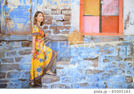 Portrait of young woman in front colorful building wall in Jodphur blue city in India 65005163