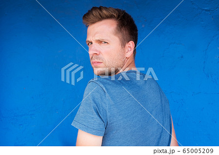 Caucasian serious man in blue t-shirt turning 65005209