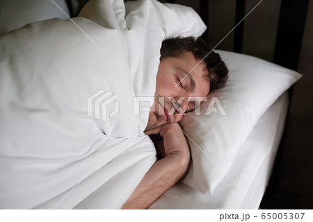 Caucasian man sleeping or napping in white bed 65005307