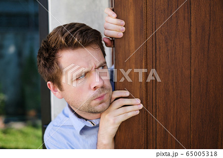 Young caucasian man with agoraphobia spying and Young caucasian man with agoraphobia spying and 65005318