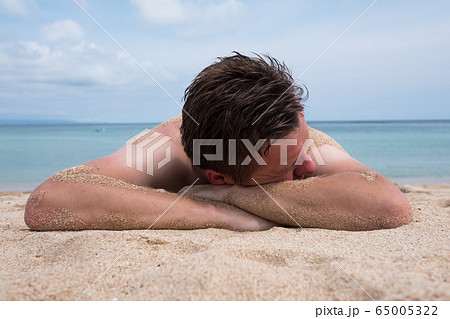 Handsome man relaxing on the beach lying and 65005322