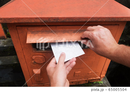 Closeup on a male hand putting a letter in a red Closeup on a male hand putting a letter in a red 65005504