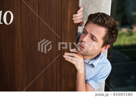 Young caucasian man with agoraphobia spying and Young caucasian man with agoraphobia spying and 65005580