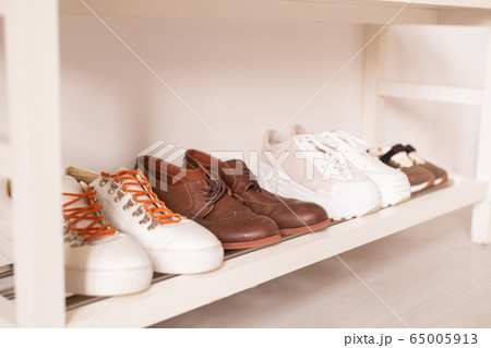Row of sportive and casual footwear by wall on white lower shelf above the floor Row of sportive and casual footwear by wall on white lower shelf above the floor 65005913