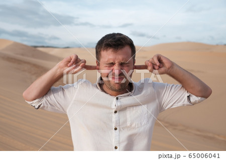 A middle-aged man stands alone in desert and 65006041