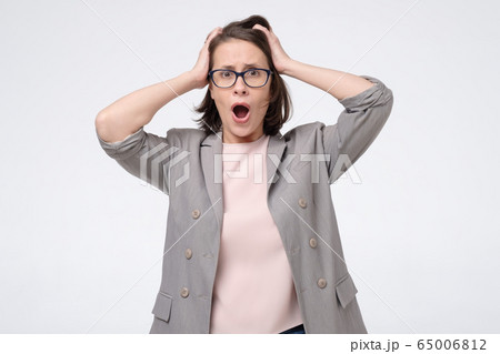 young angry shocked woman in glasses holding hands 65006812
