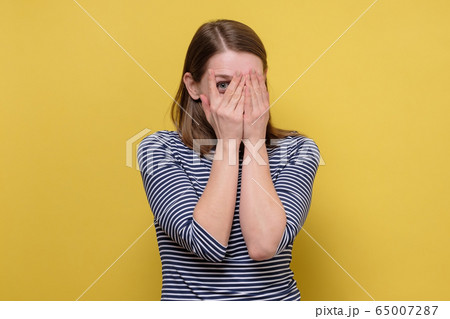 curious woman looking through fingers, peeking curious woman looking through fingers, peeking 65007287