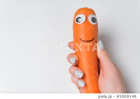 Hand holding carrot with fun Googly eyes and smile 65009146