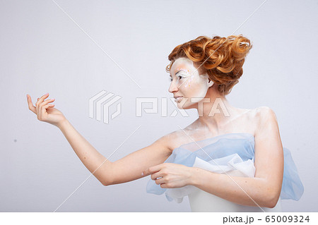 Image of a young beautiful red-haired woman. Young woman with an unusual hairstyle and unusual make-up. 65009324