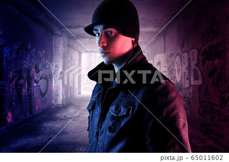 Young man on a dark alley full of graffities 65011602