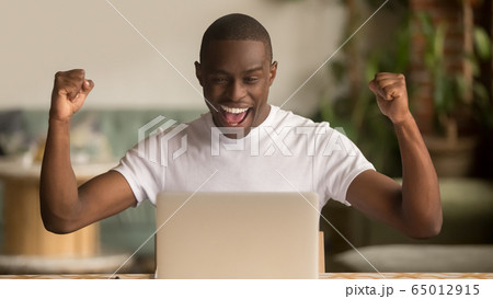 Overjoyed happy african american businessman excited winner looking at laptop 65012915
