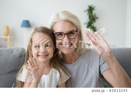 Portrait of grandmother and kid waving hands looking at camera 65013245