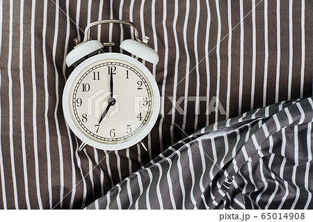 White vintage alarm clock on pillow in the bed. White vintage alarm clock on pillow in the bed. 65014908