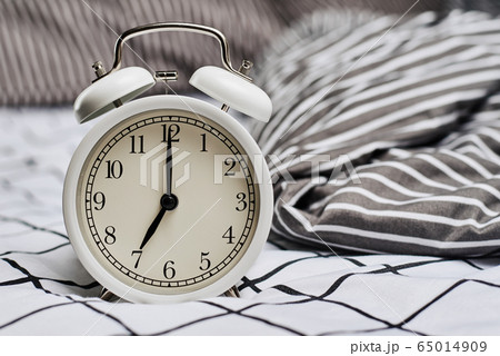 White vintage alarm clock and pillows in the bed. White vintage alarm clock and pillows in the bed. 65014909