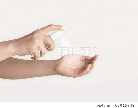 Antiviral hygiene measures. Close up of female hands applying antiseptic on light background Antiviral hygiene measures. Close up of female hands applying antiseptic on light background 65015548