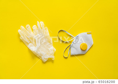 Respirator ffp and rubber gloves lie on a yellow background. Anti-virus protection kit against covid-19. Coronavirus pandemic 2019. Respirator ffp and rubber gloves lie on a yellow background. Anti-virus protection kit against covid-19. Coronavirus pandemic 2019. 65016200