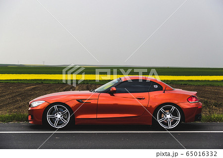 Red luxury sedan with black tuning on the highway in the fog 65016332