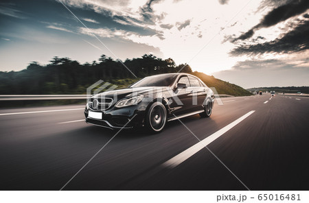 Black sedan travelling in the highlands in a sunny day Black sedan travelling in the highlands in a sunny day 65016481