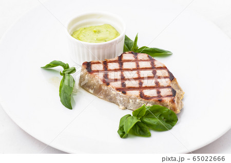Steak with sauce and basil on a white plate 65022666