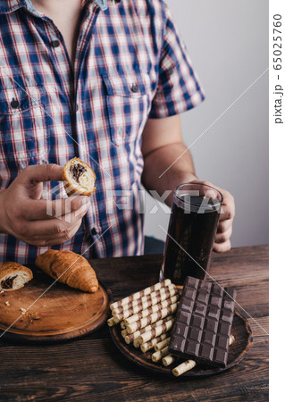 Overweight man with big amount of sugary food 65025760