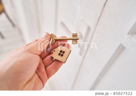 Modern light lobby interior. Men hand holding key with house keychain. Real estate, moving home or renting property. Mortgage concept. Modern light lobby interior. Men hand holding key with house keychain. Real estate, moving home or renting property. Mortgage concept. 65027522