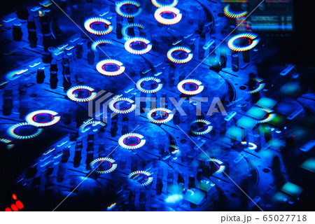 DJ mixer in a nightclub with a background of glowing lights from buttons 65027718