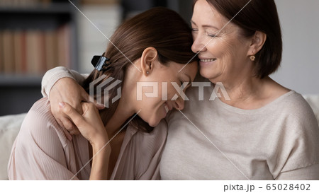 Smiling mature mother hugging adult daughter, enjoying tender moment 65028402