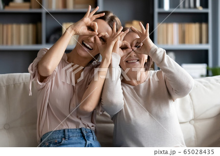 Funny portrait adult daughter and mature mother making binoculars gesture Funny portrait adult daughter and mature mother making binoculars gesture 65028435