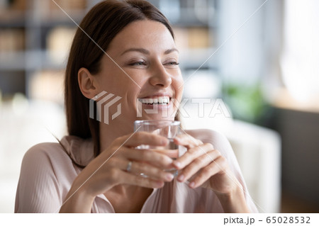 Smiling beautiful woman holding glass of pure mineral water 65028532