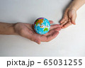 baby and hand of adult man holding a small globe during the epidemic 65031255