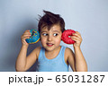 boy is holding two colored doughnuts blue and red in front 65031287