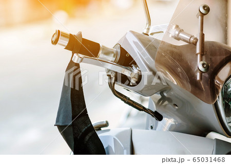 A mask hanging on a motorcycle handle to prevent germs (Covid-19) on roadside in the city. Corona virus protection concept. A mask hanging on a motorcycle handle to prevent germs (Covid-19) on roadside in the city. Corona virus protection concept. 65031468