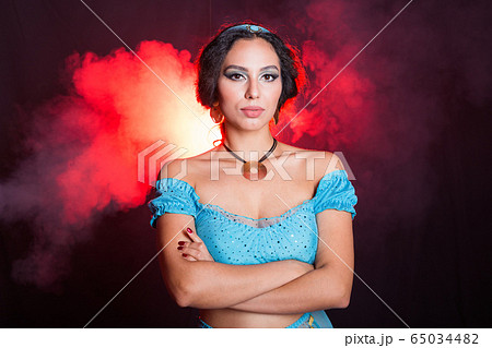Magic, cosplay, carnival and fairy tale concept - Portrait of a young woman in the image of an Eastern fairy Princess on dark background. 65034482