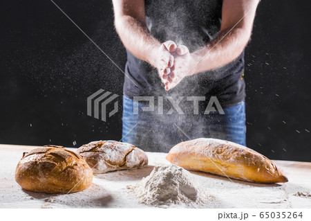 The male hands in flour and rustic organic loaf of bread The male hands in flour and rustic organic loaf of bread 65035264