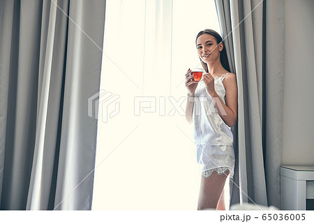 Positive attractive lady drinking tasty beverage in morning 65036005