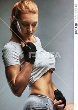Sporty woman portrait in dark sportswear on a gray background. Beautiful body, sport banner, copy space Sporty woman portrait in dark sportswear on a gray background. Beautiful body, sport banner, copy space 65038846