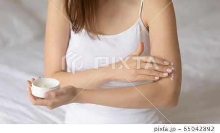 Young woman apply moisturizing body cream on arm 65042892