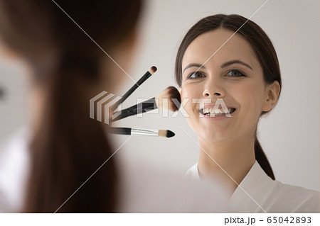 Smiling young woman doing make up at home 65042893